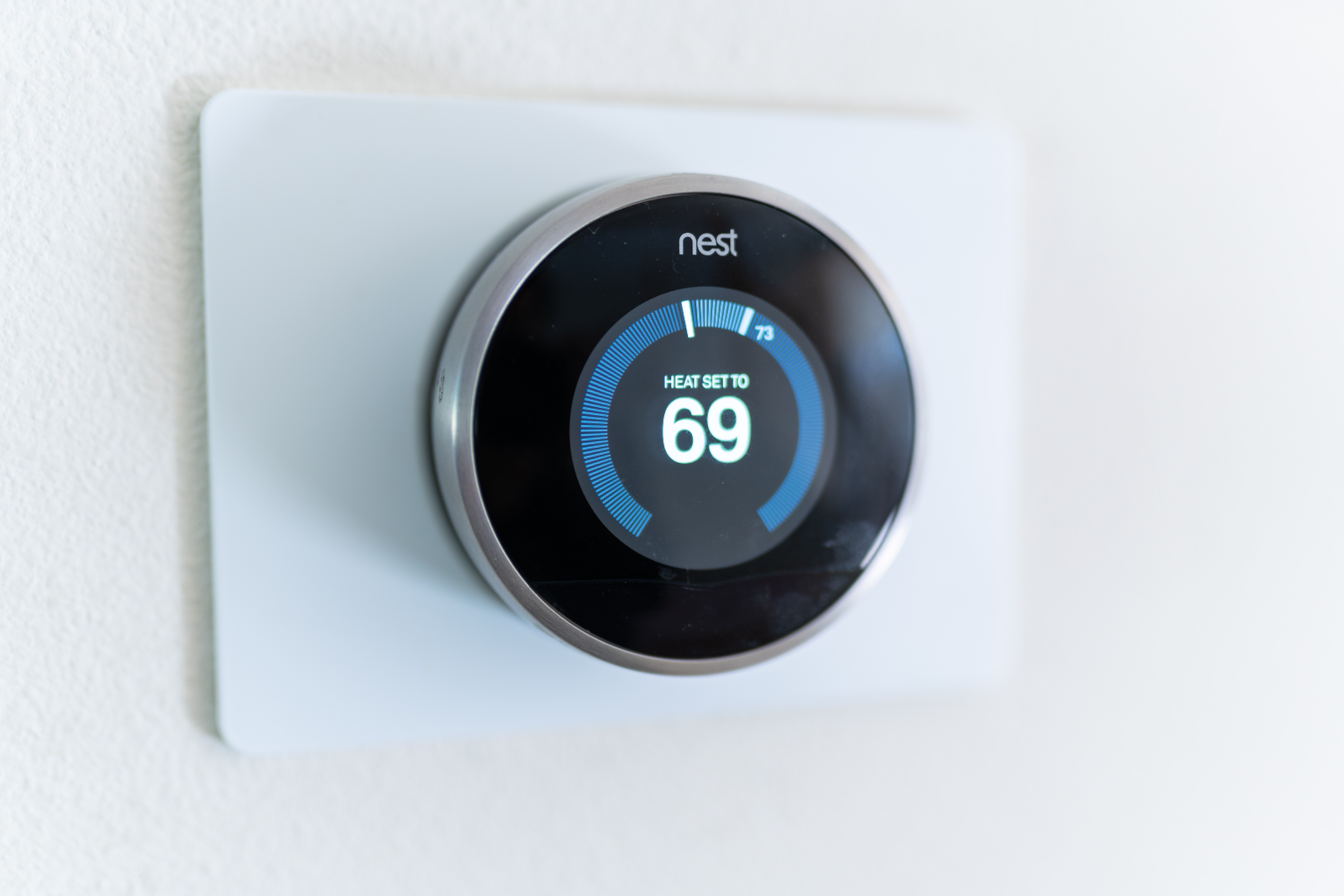 A Nest thermostat set to 69 degrees on a white wall.